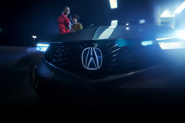 2024 Acura Integra A-Spec in Liquid Carbon Metallic front close up of illuminated badge at night (Premium Sport Compact).