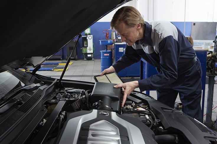 Acura mechanic replacing the engine air filter under the hood.