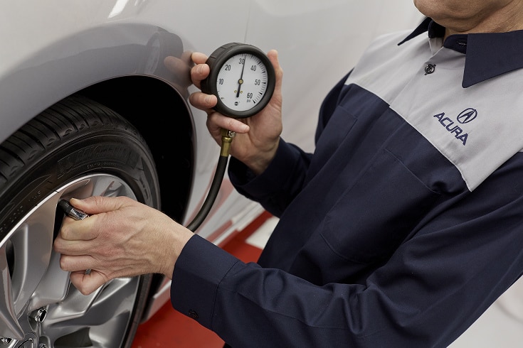 Acura technician checking tire pressure.