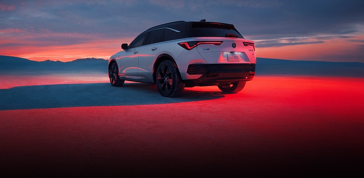 2024 Acura ZDX type S in Snowfall Pearl back parked on sand at sunset (Premium All-Electric SUV).