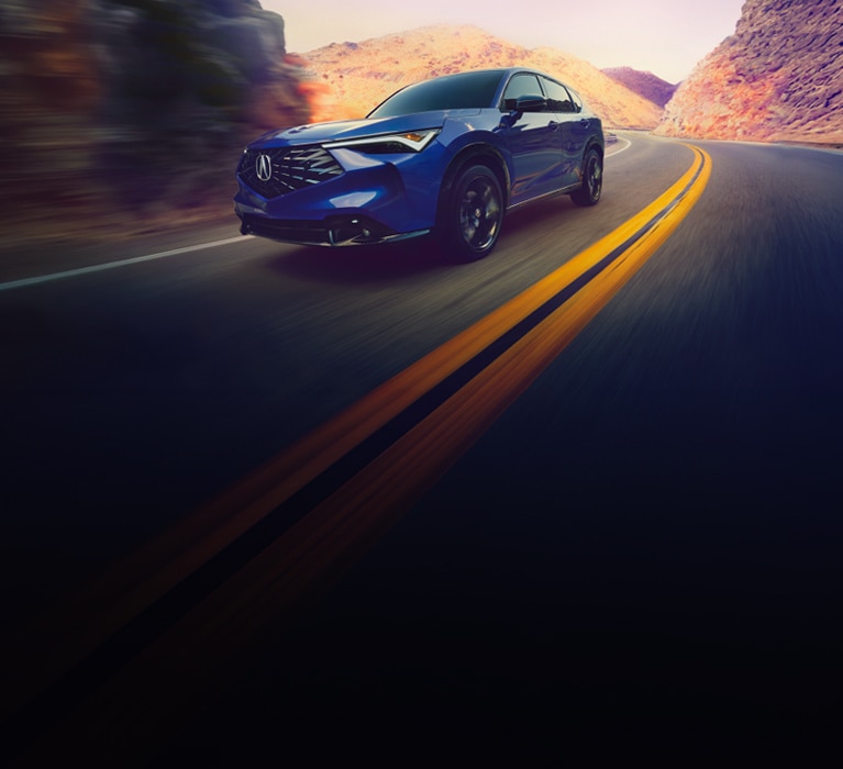 2025 Acura ADX A Spec in Double Apex Blue Pearl II front driving on a winding mountain road (Premium Compact SUV).