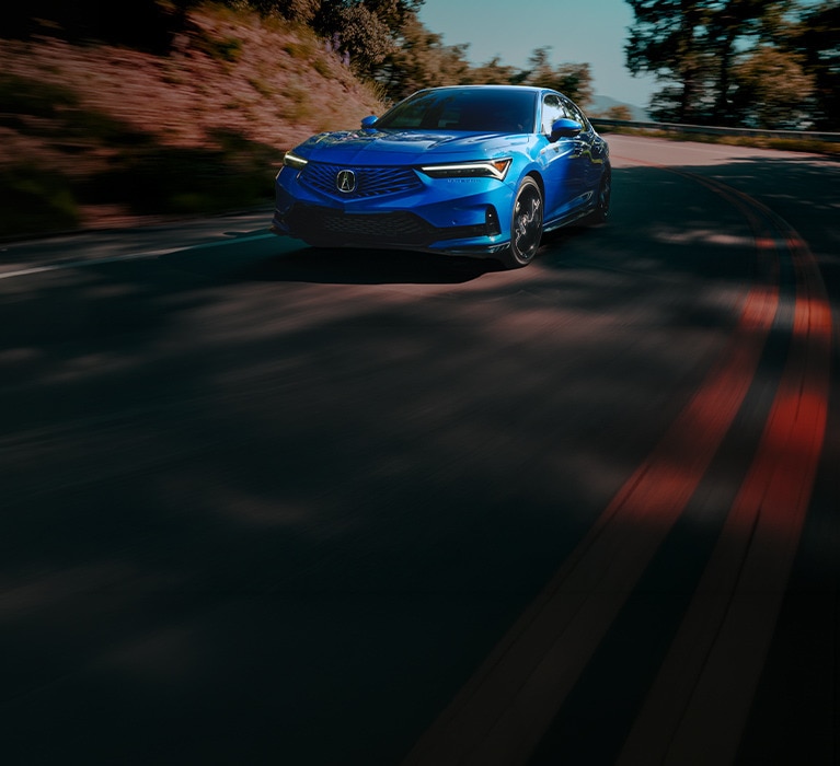 2026 Acura Integra A-Spec in Double Apex Blue Pearlfront driving on a winding mountain road (Premium Sport Compact).