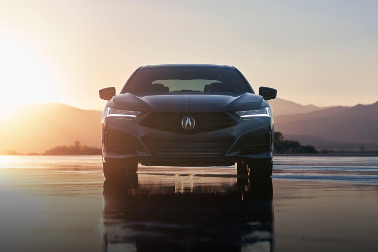 2025 Acura TLX A-spec in Liquid Carbon Metallic front on a wet surface with a sunset background (Premium Sport Sedan).