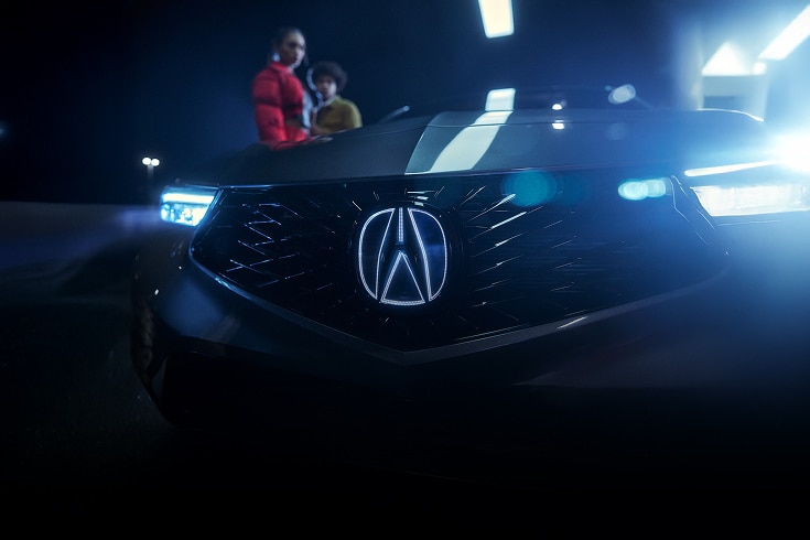 2024 Acura Integra A-Spec in Liquid Carbon Metallic front close up of illuminated badge at night (Premium Sport Compact).