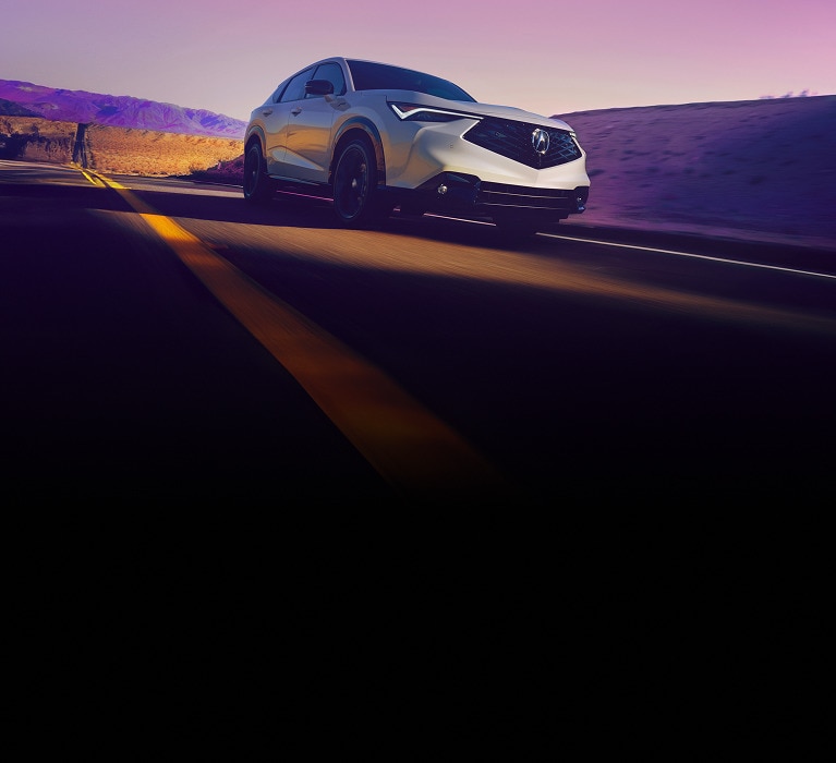 2026 Acura ADX A-Spec in Platinum White Pearl front driving on a desert road at sunset (Premium Compact SUV).