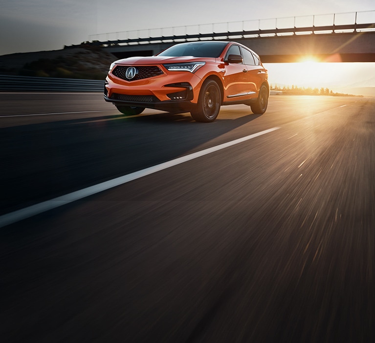 2021 Acura RDX PMC Edition in Thermal Orange Pearl front on highway (Premium Sport Crossover SUV).