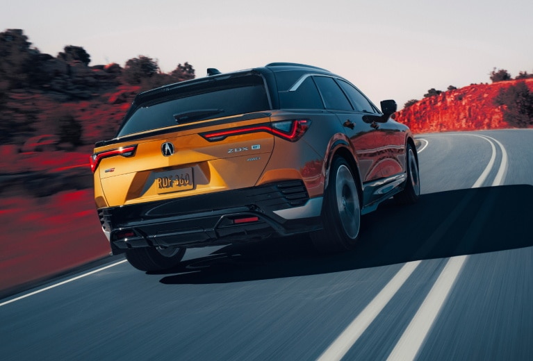 Yellow Acura ZDX rear view driving down a road